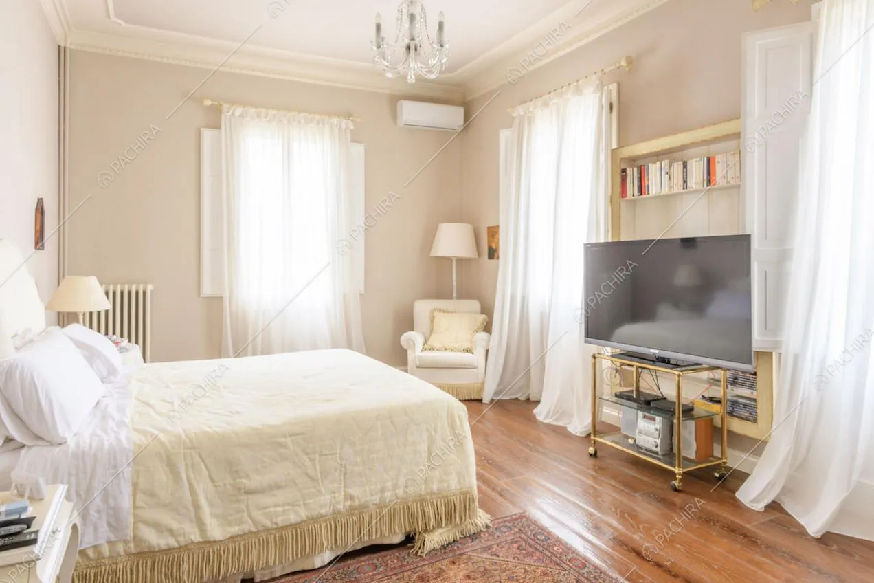 Luminosa camera da letto matrimoniale con boiserie sul soffitto e pareti dalle nuances delicate