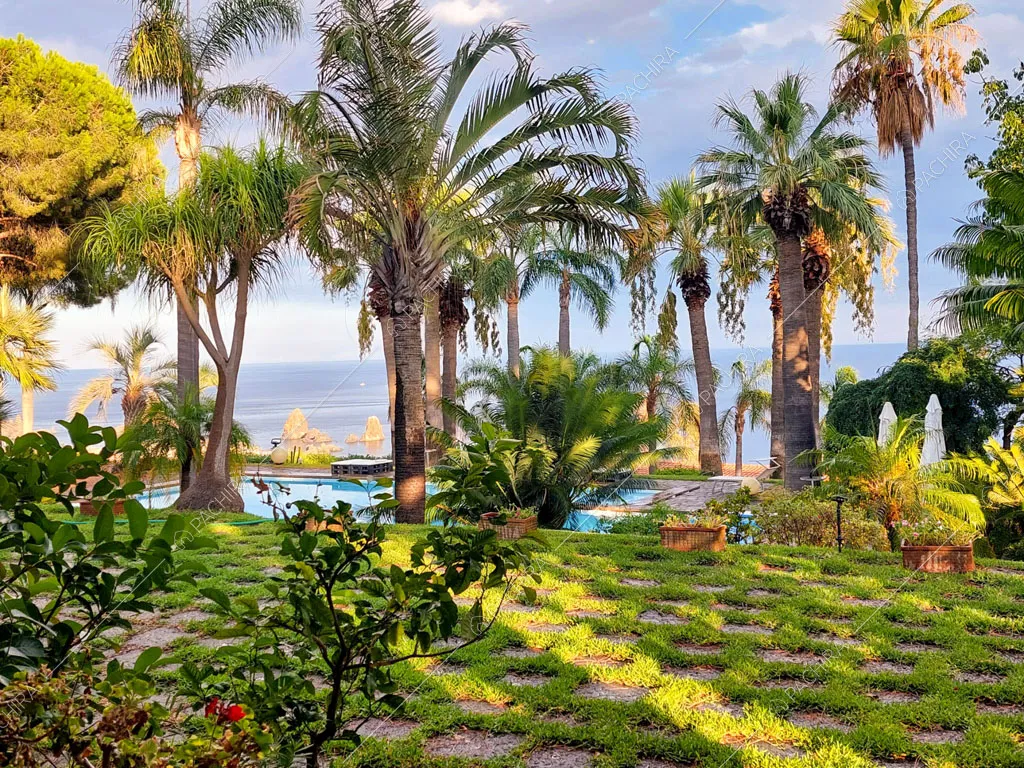 Grande giardino con palme, piscina e vista sul mare