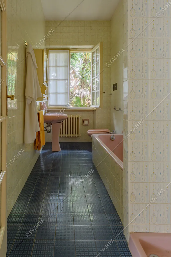 Luminoso bagno con pavimento in piastrelle blu e vasca rosa