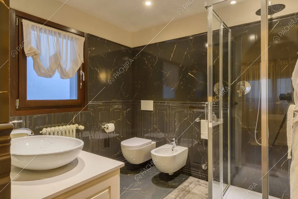Box doccia nel grande bagno con pavimento e pareti in marmo nero