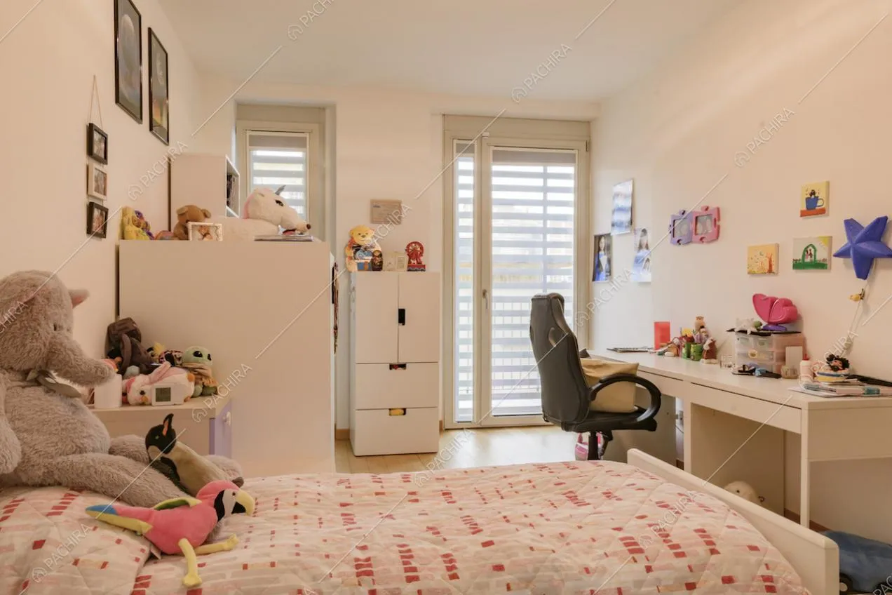 Camera da bambini con scrivania e porta-finestra per accedere al balcone