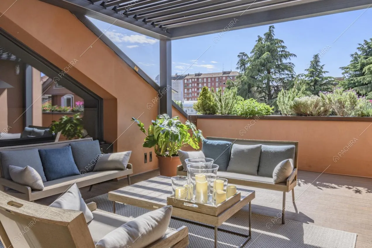 Terrazza coperta con divanetti, cuscini e tavolino di legno