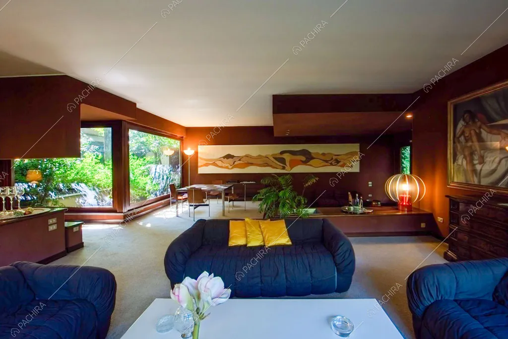 Divani blu nella grande zona living con pareti marroni e vetrate con vista sul giardino