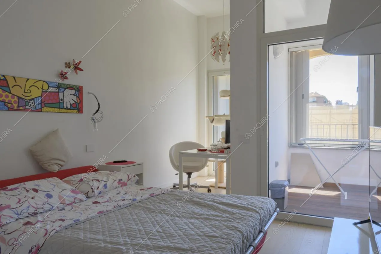 Piccola scrivania con poltroncina bianca e letto matrimoniale