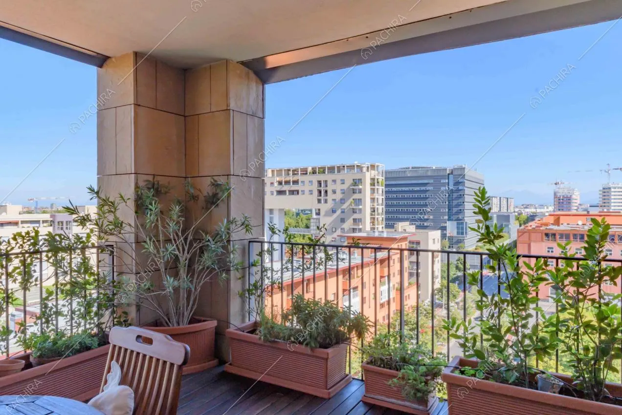 Dalla terrazza con tavolino da pranzo e sedie, vista sullo skyline milanese