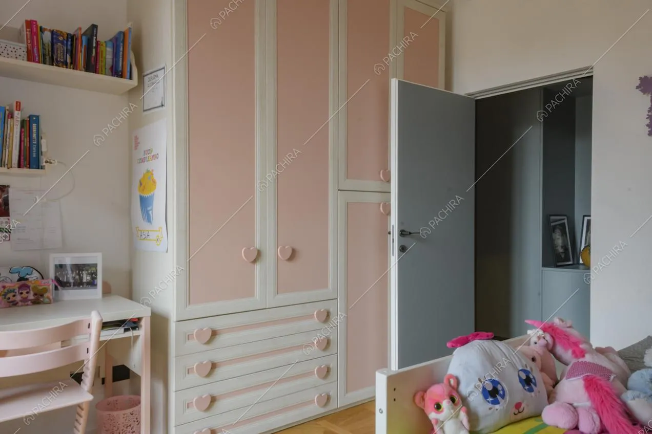 Armadio rosa e bianco, scrivania e pupazzi nella cameretta