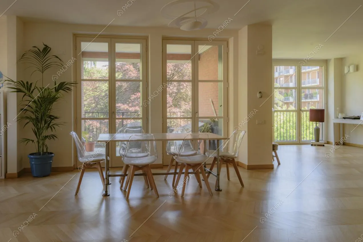 Ampie porte finestre lungo le pareti della zona giorno e tavolo da pranzo con sedie
