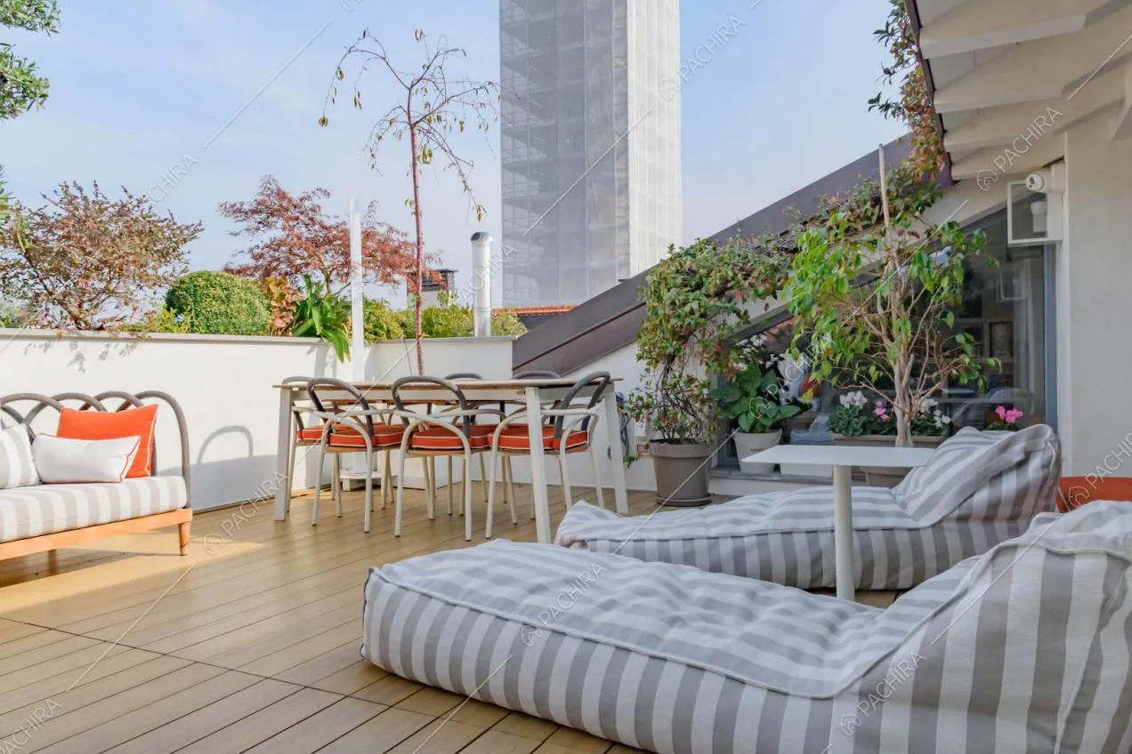 Sulla terrazza con pavimento in parquet da esterni, pouf e tavolo da pranzo