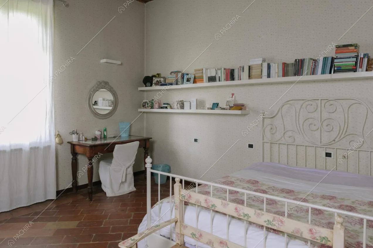Camera da letto dai colori chiari e pavimento in pietra