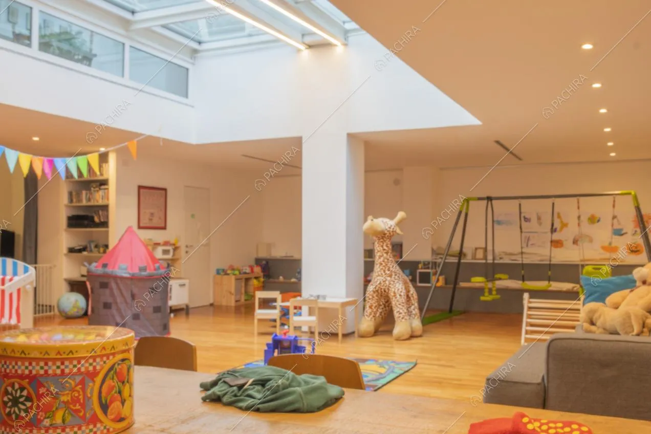 Area giochi con altalene e grandi vetrate sul soffitto