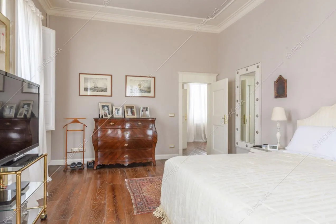 Letto matrimoniale nella camera con pavimento in parquet e boiserie sul soffitto