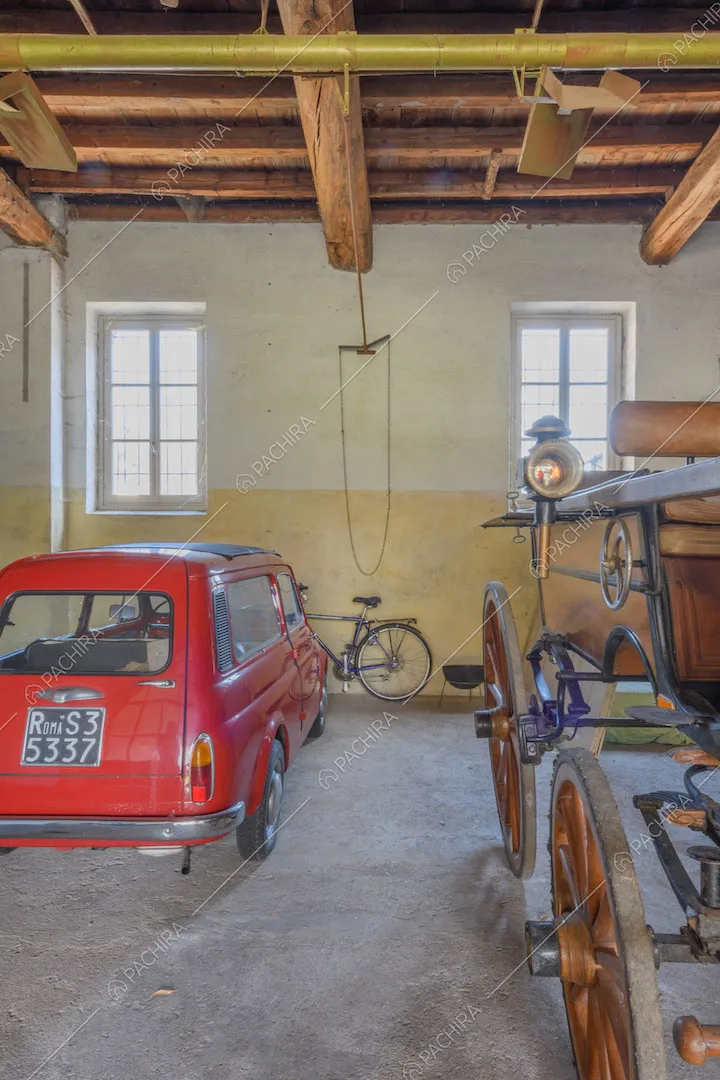 Garage con soffitto in travi in legno a vista e pareti gialle e bianche