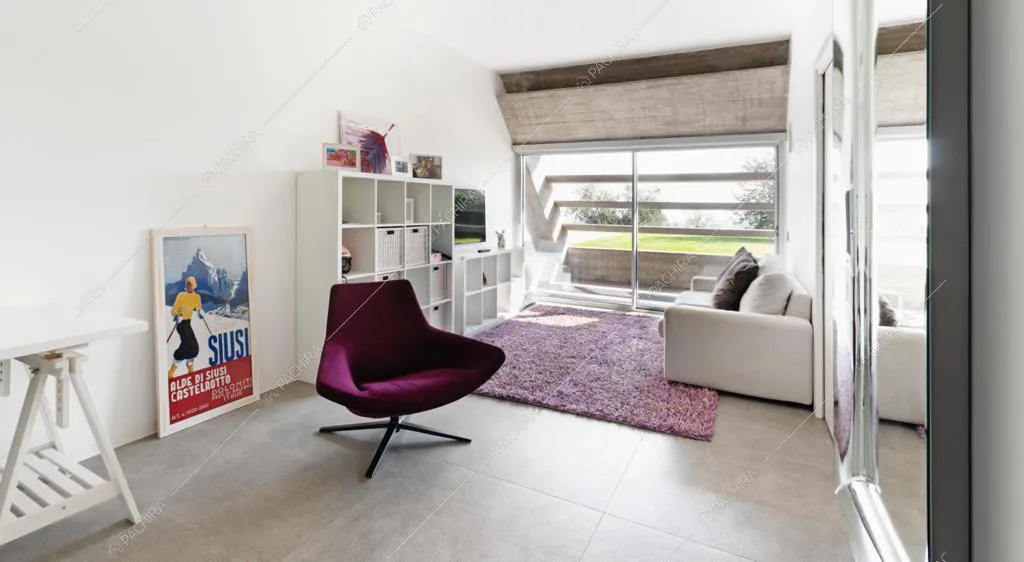 Divano bianco sopra al tappeto viola e poltroncina di design