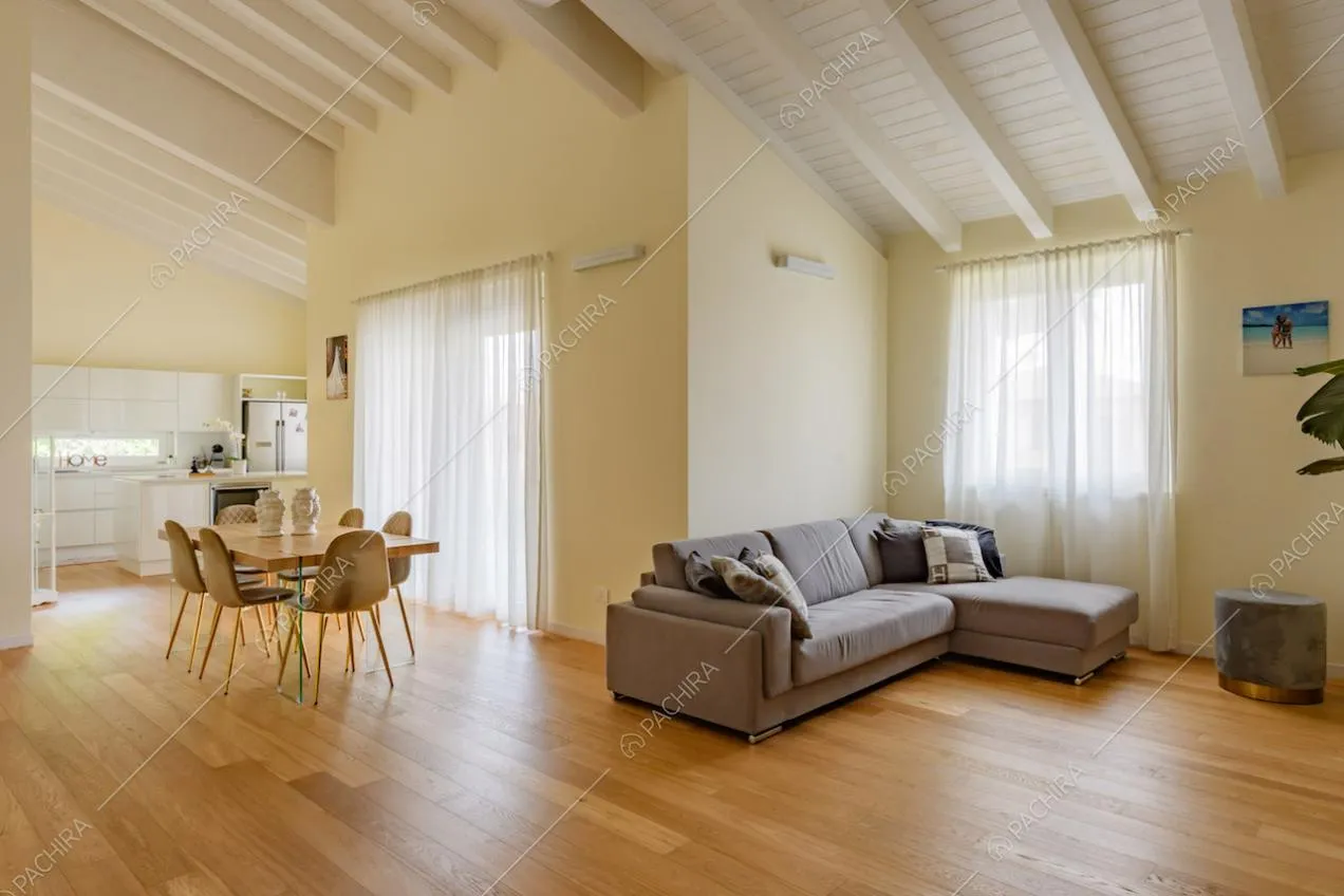 Divano angolare grigio nella zona living con travi a vista sul soffitto