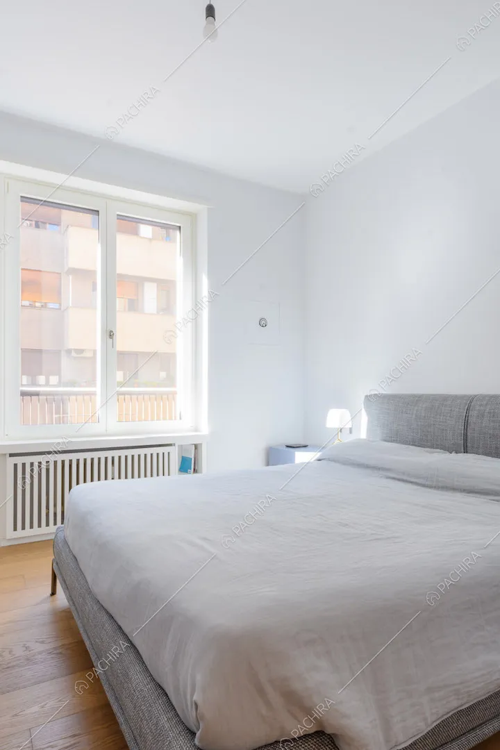 Luminosa camera da letto matrimoniale con pavimento in parquet e pareti bianche
