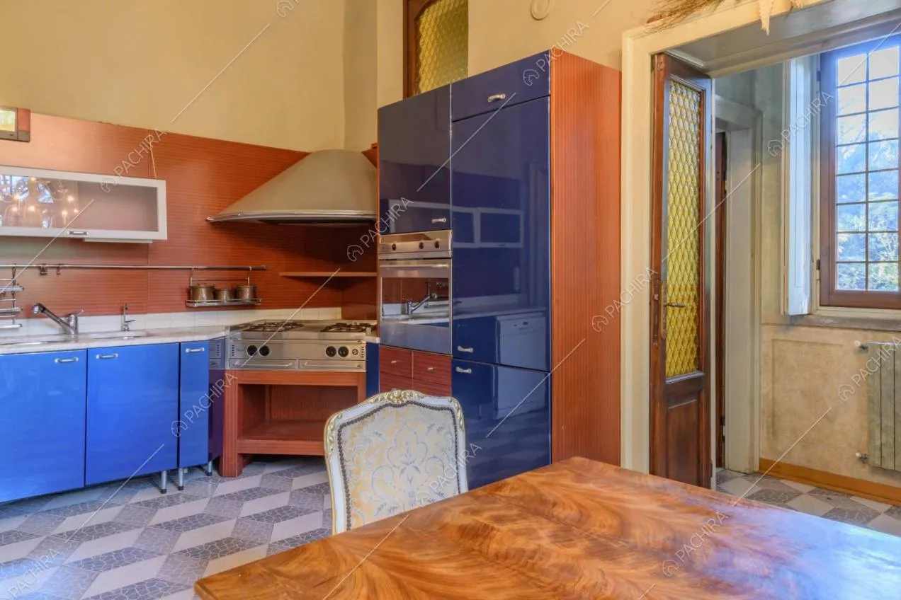 Cucina a parete rossa e blu con fornelli a gas, pavimento in piastrelle e tavolo in legno