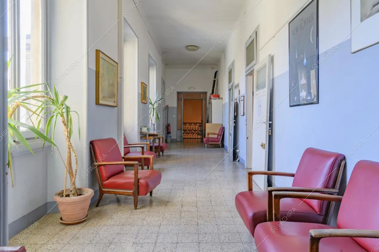 Corridoio con poltrone in pelle rossa, pavimento in piastrelle e pareti azzurre e bianche