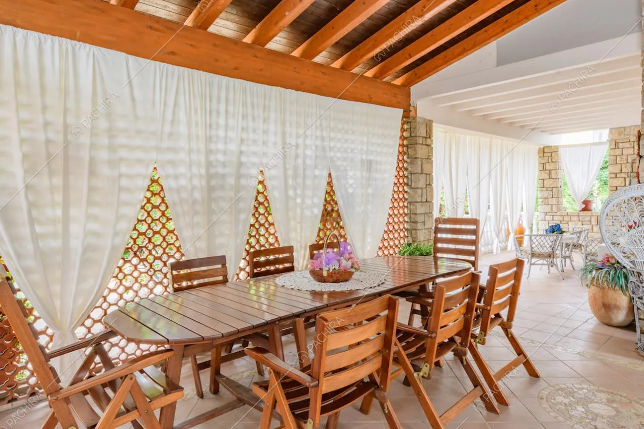 Tavolo da pranzo e sedie in legno nella veranda con travi a vista