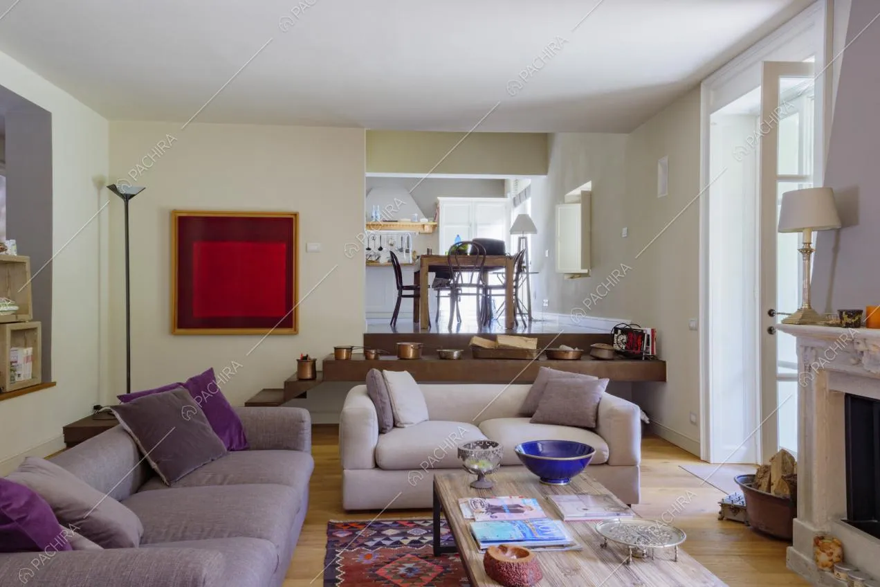 Nel salotto con camino, pavimento in parquet e divani viola vista sulla cucina