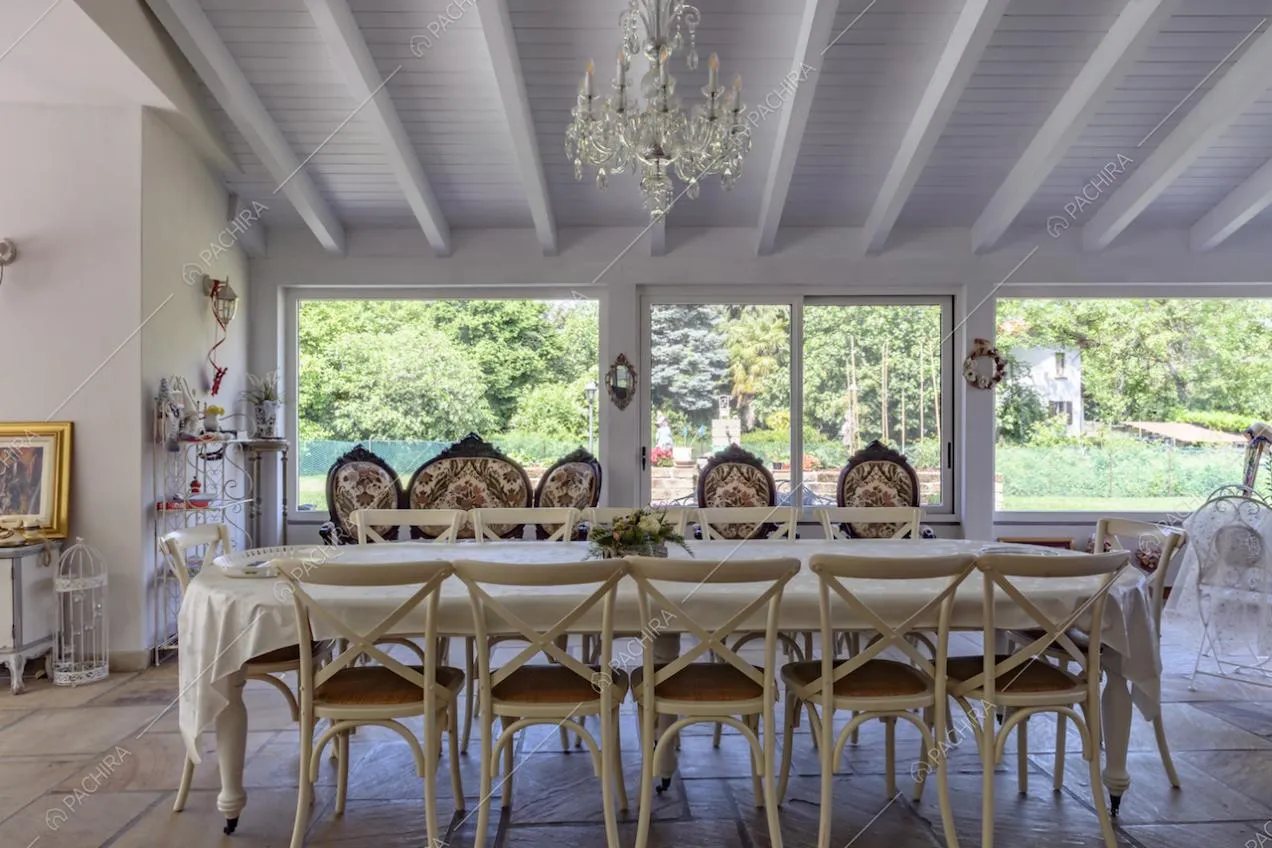 Nella veranda illuminate dalle ampie vetrate e con travi in legno a vista sul soffitto, grande tavolo da pranzo