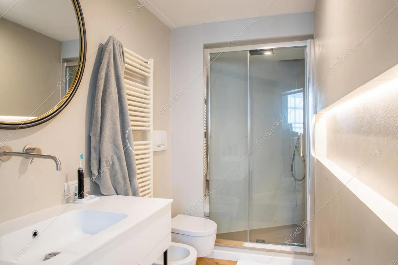 Bagno dalle pareti bianche con ampio box doccia e pavimento in parquet