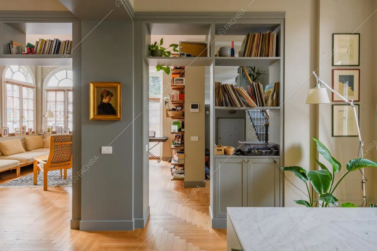 Dalla penisola della cucina vista sul luminoso salotto con porta d'ingresso e sulla colonna grigia