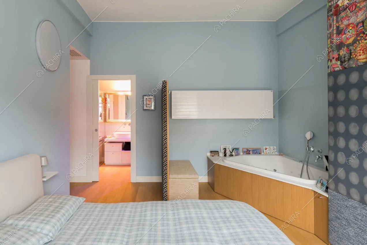 Camera da letto matrimoniale con pareti azzurre e vasca da bagno