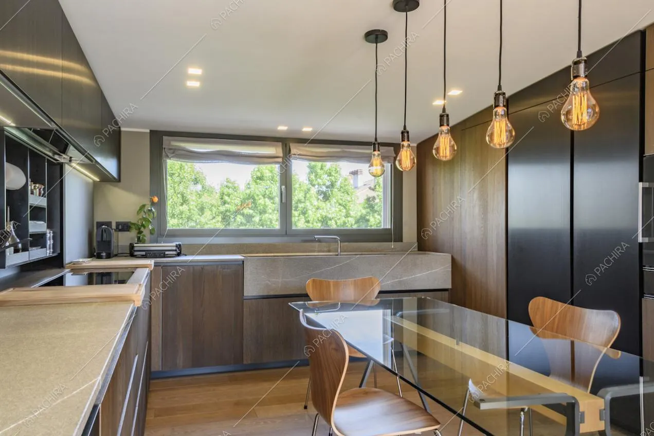 Tavolo da pranzo in vetro con sedie in legno e lampade appese al soffitto