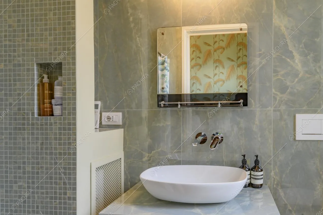 Bagno con pareti in marmo e box doccia con piastrelle
