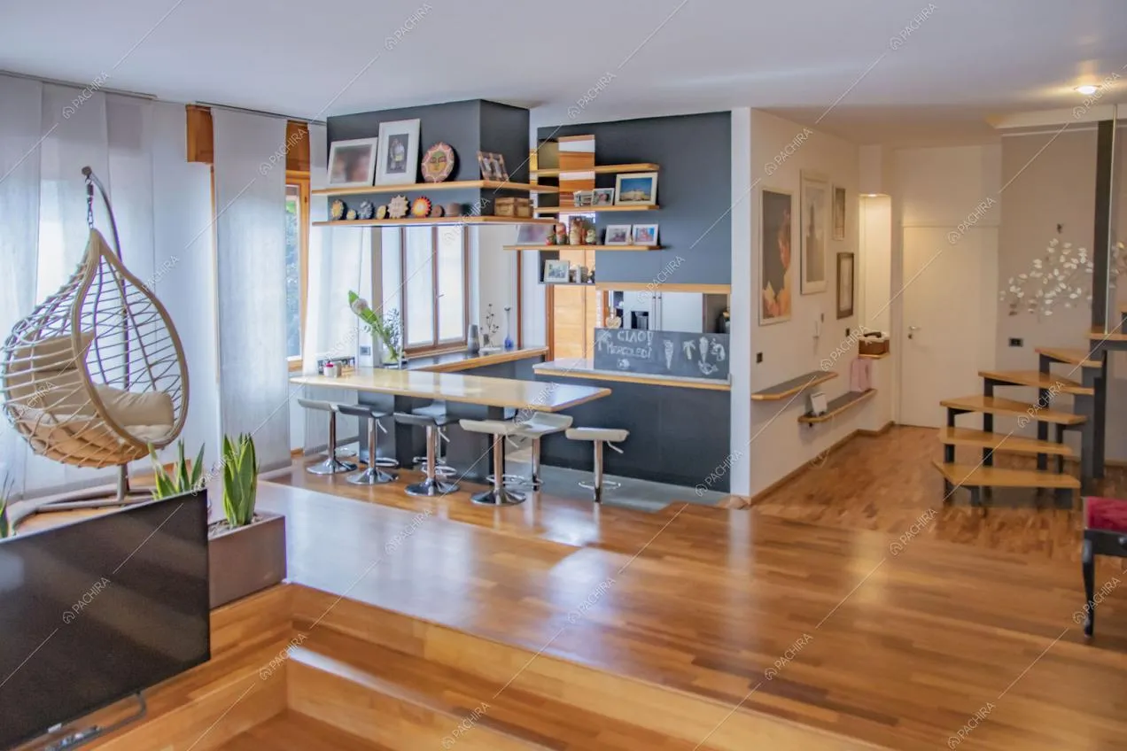 Dai divani della zona living vista sulla cucina con bancone e sgabelli