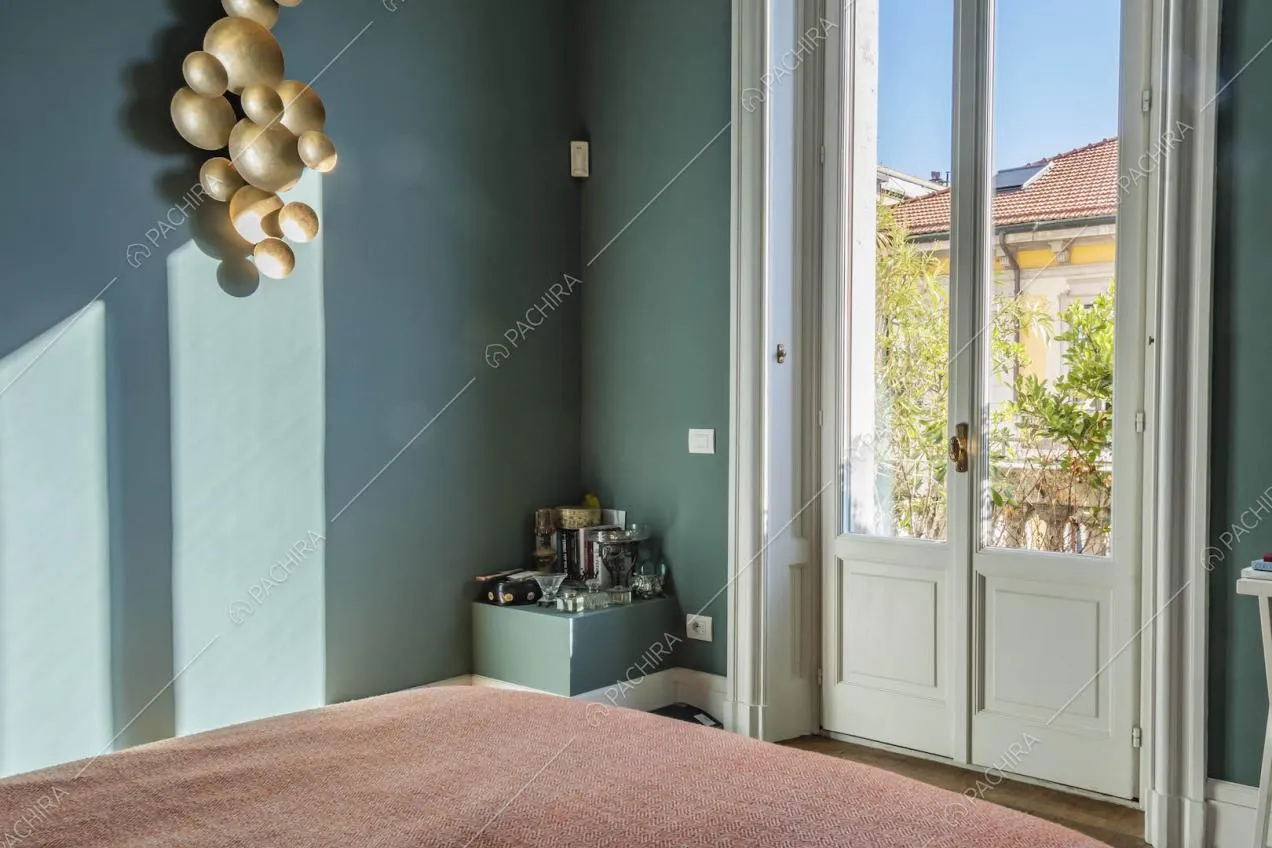 Luminosa camera da letto con porta-finestra con boiserie e pareti blu petrolio