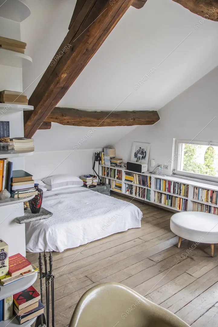 Travi a vista e mensole con libri nella camera 
