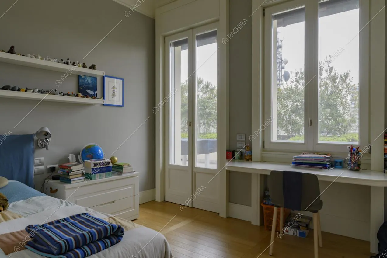 Camera da letto con pavimento in parquet, scrivania, pareti grigie e porta-finestra
