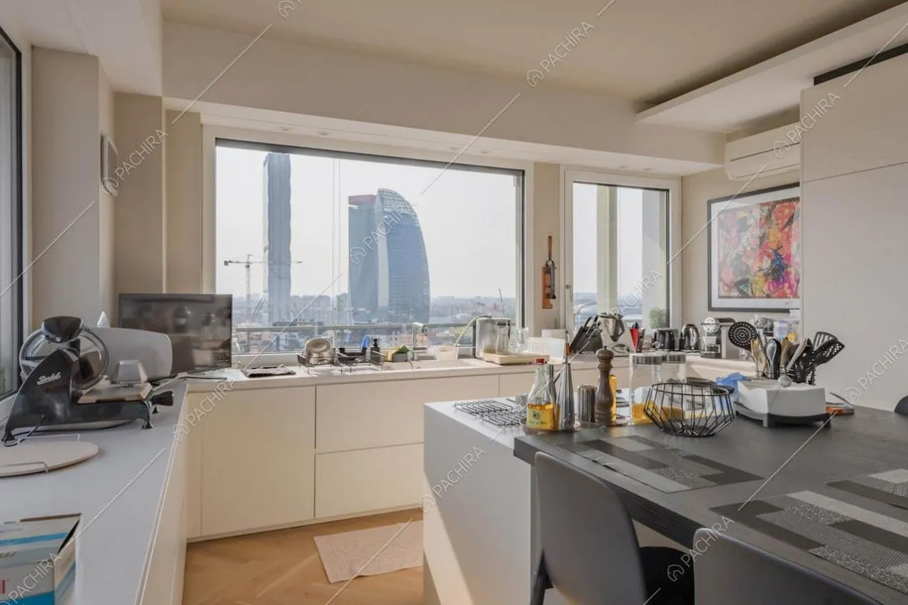 Pavimento in parquet nella cucina con vista sullo skyline e isola con tavolo accostato