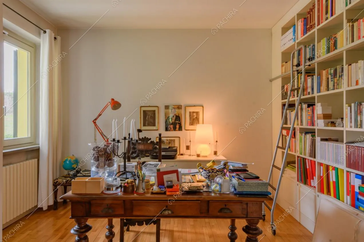 Studio con scrivania in legno, libreria bianca, vetrate e pavimento in parquet