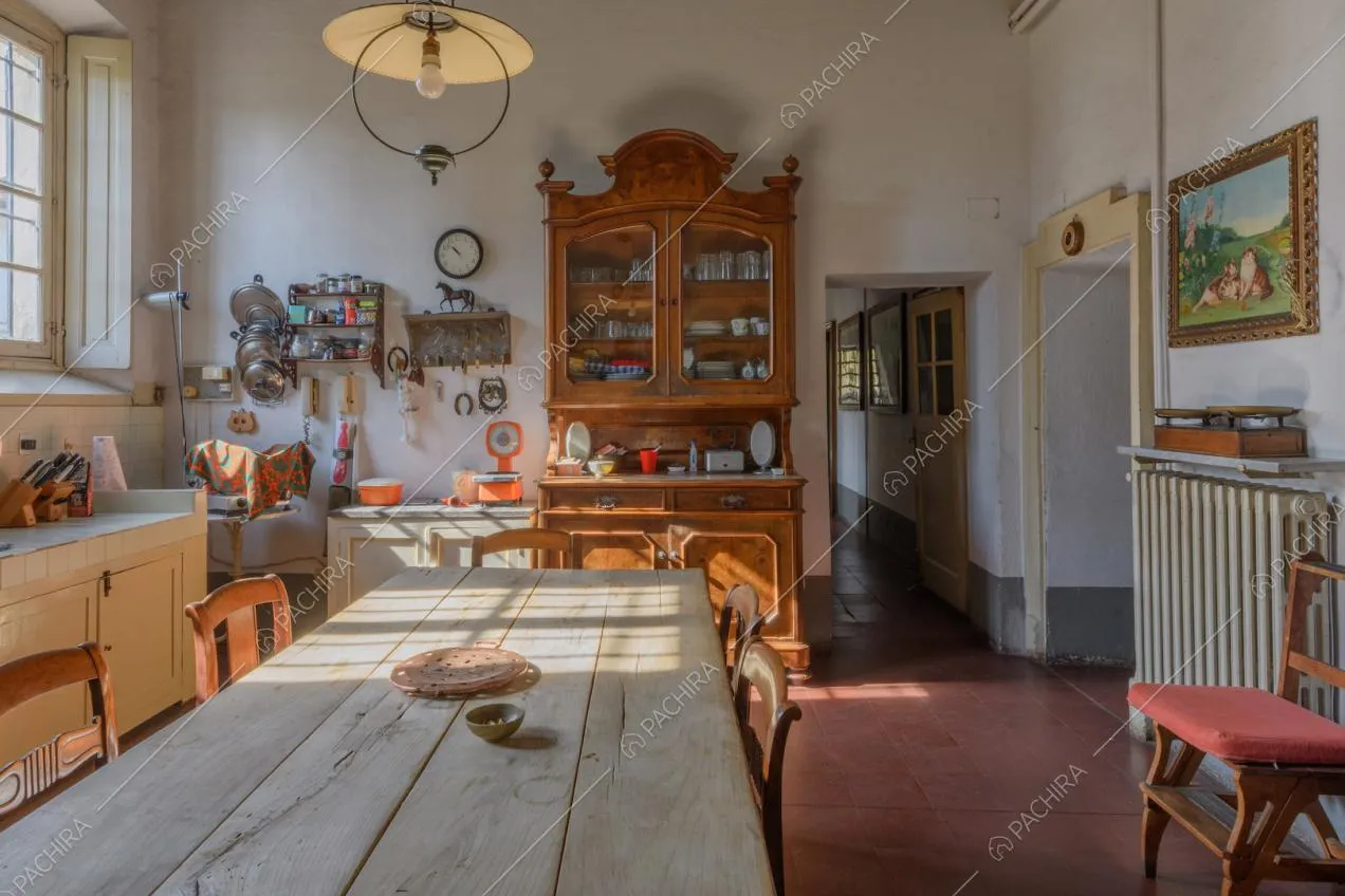 Grande cucina bianca a parete con tavolo da pranzo in legno e pavimento in cotto
