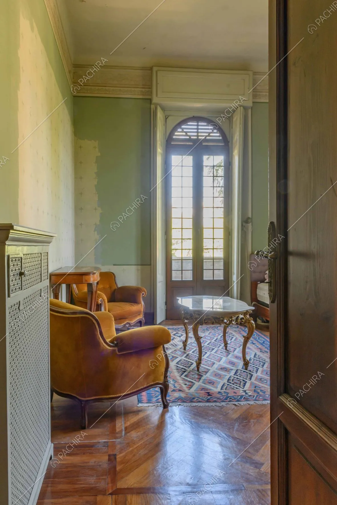 Vista sul salotto dalle pareti verdi e dal pavimento in parquet