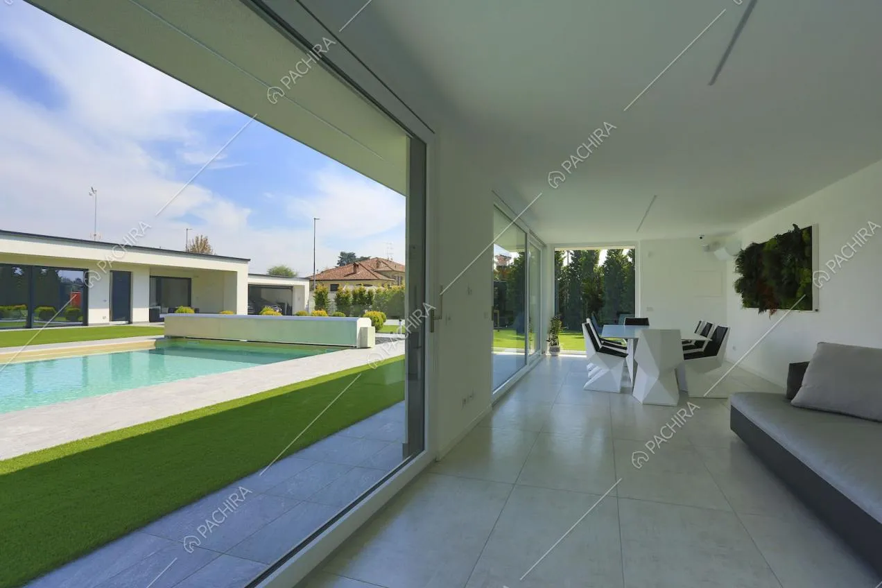 Sala da pranzo dalle ampie vetrate e scorcio sulla piscina tramite le ampie vetrate