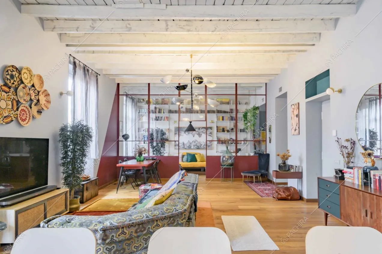 Dall'isola della cucina vista sul salone e sulle vetrate rosse in stile industriale che separano il salotto
