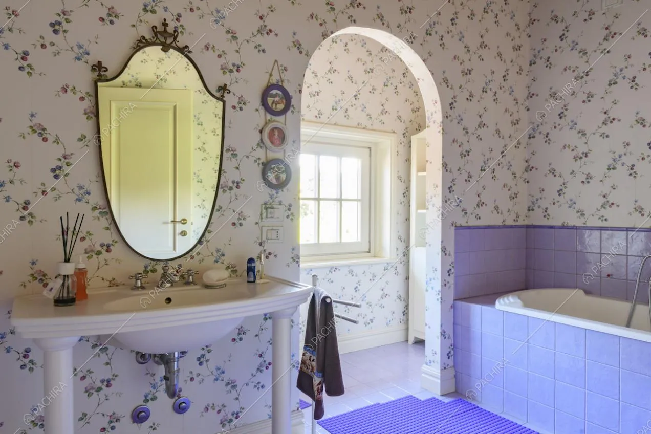 Bagno con pareti rivestite in carta da parati a fantasia floreale