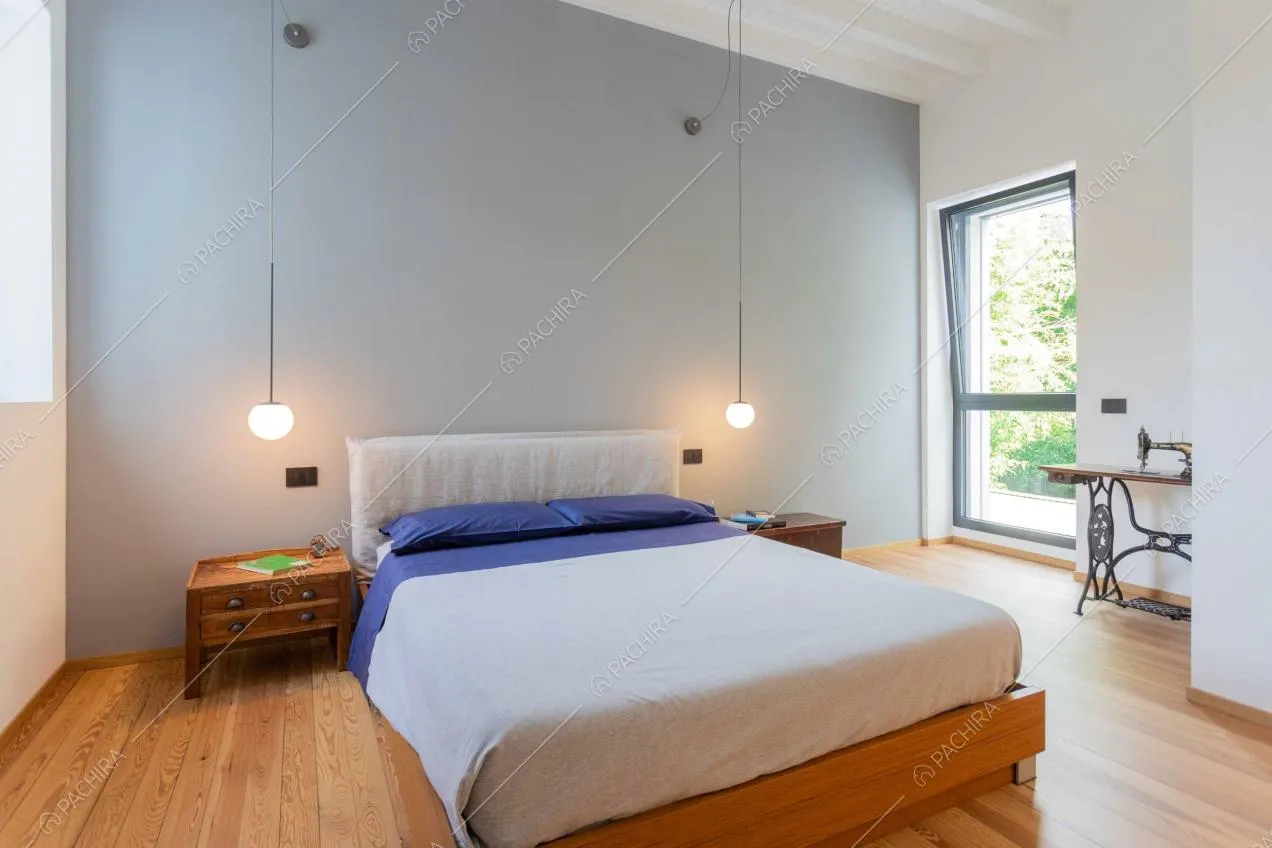 Camera da letto dalle pareti grigia e bianche, dal pavimento in parquet e con travi a vista