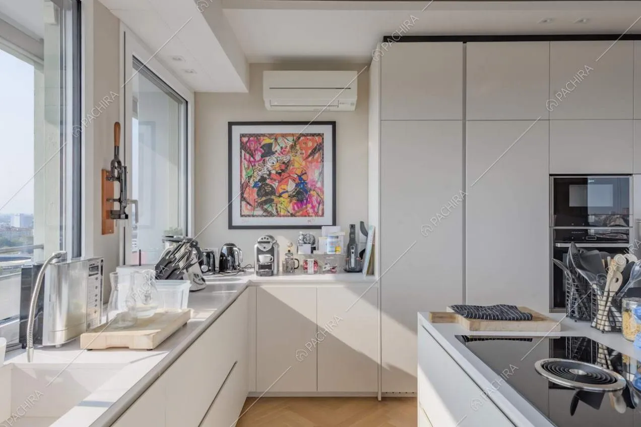 Pavimento in parquet nella cucina bianca a isola con fornelli a induzione