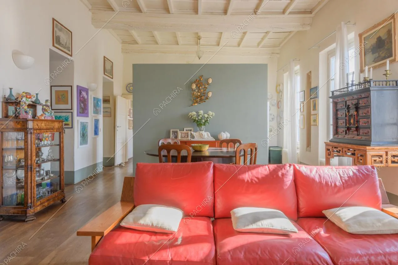 Divano rosso nella zona living con pavimento in parquet e soffitto a cassettoni bianco