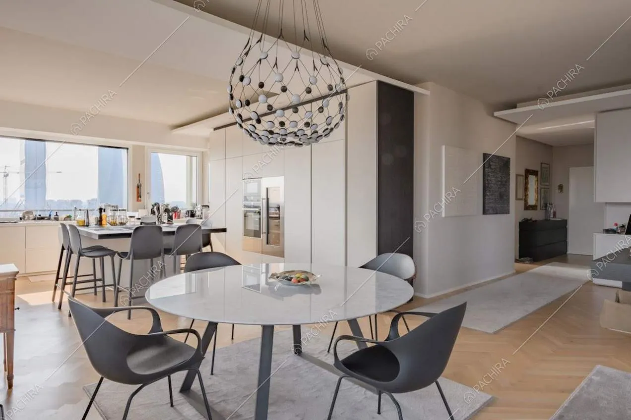 Luminosa zona living con pavimento in parquet a spina di pesce e tavolo da pranzo rotondo