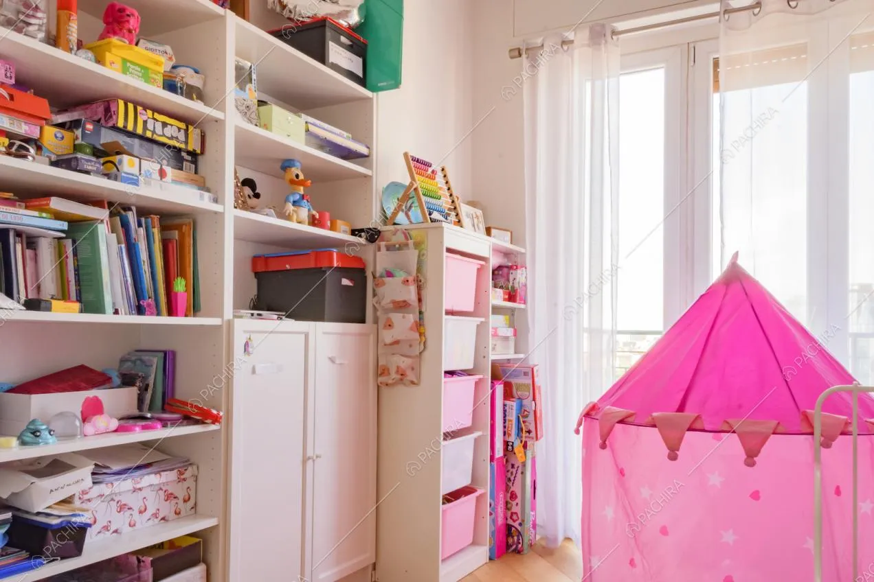 Scaffale bianco con libri e giochi nella cameretta