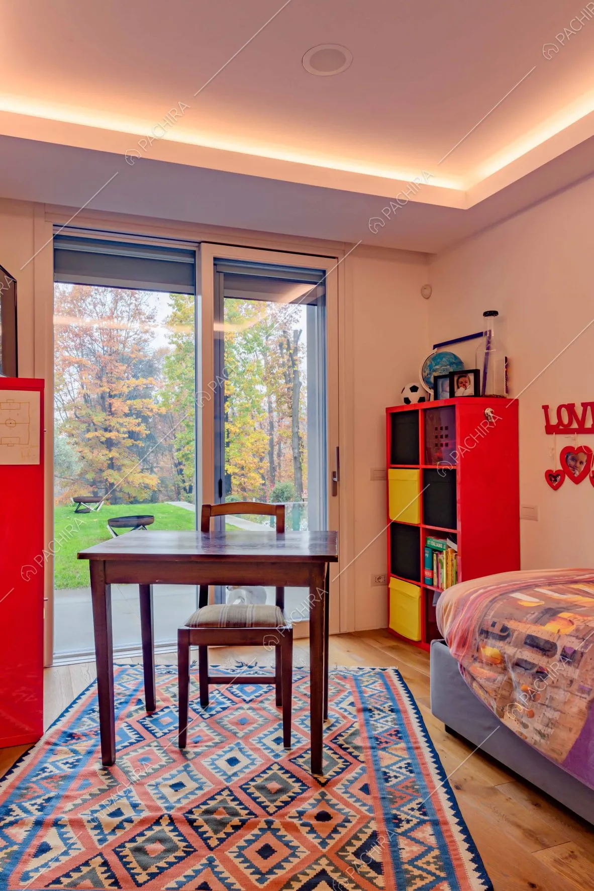 Camera da letto con vetrata da cui si accede al giardino, pareti bianche e scrivania