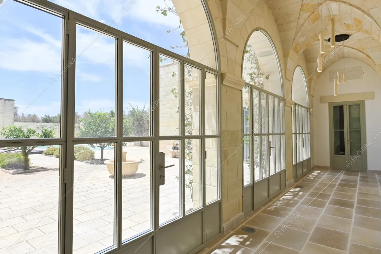Dal corridoio, tramite le porte-finestre in stile industriale, vista sul cortile