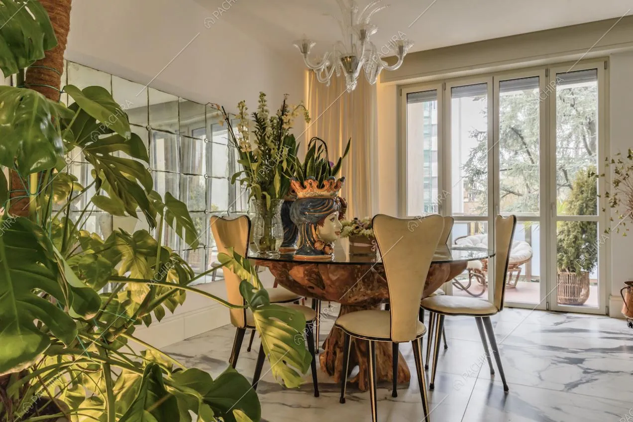 Tavolo da pranzo in legno, sedie bianche di design e specchiera délabré nella sala dal pavimento in marmo