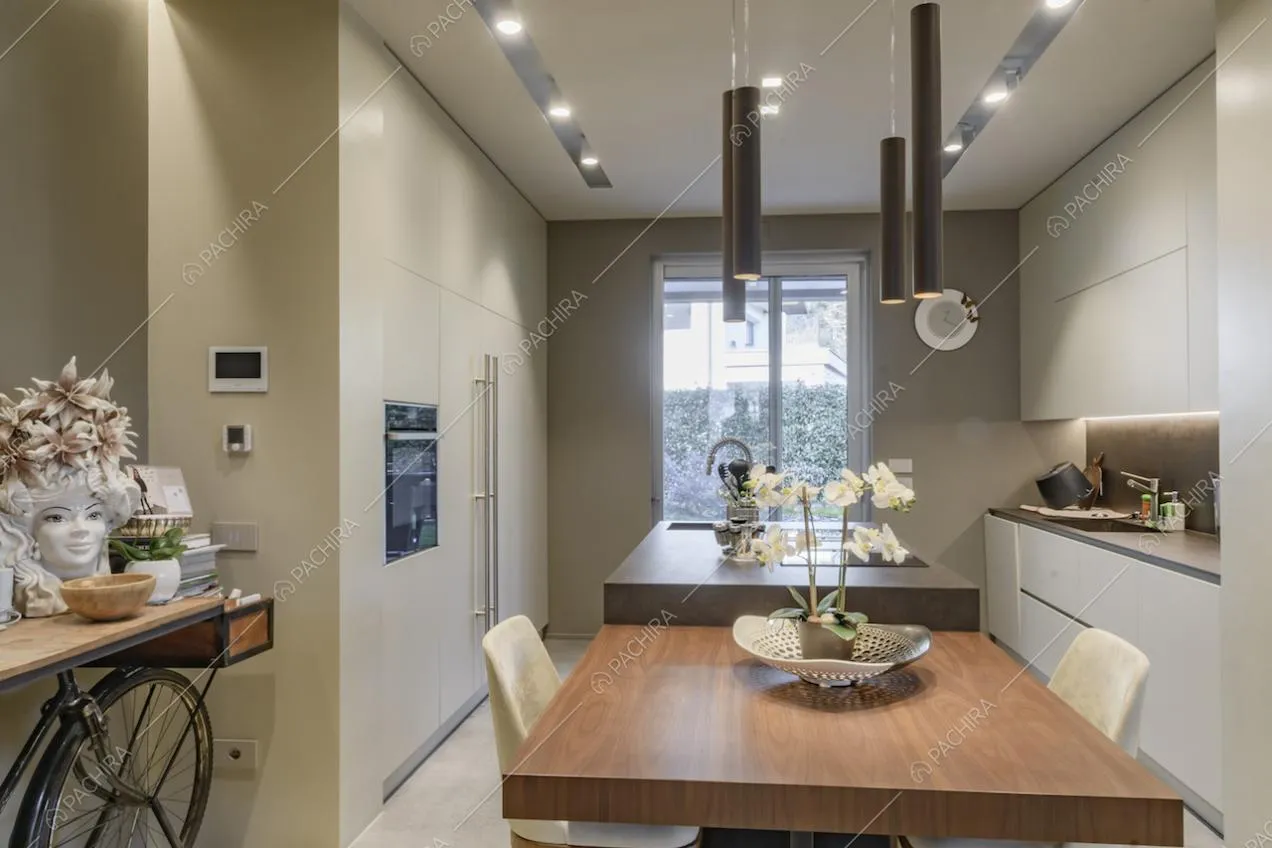 Nella luminosa cucina con isola, fornelli a induzione, tavolo da pranzo in legno e porta-finestra