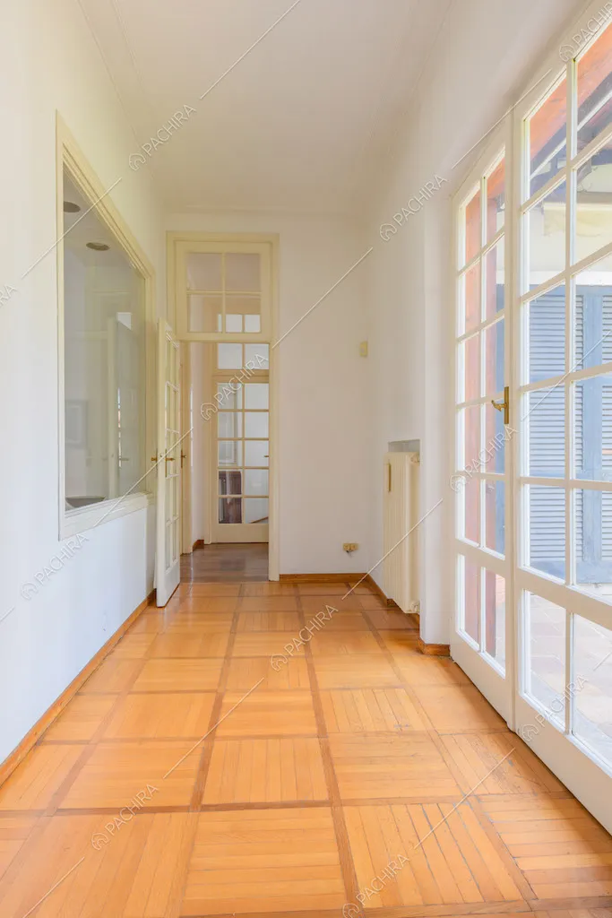 Corridoio con pavimento in parquet e porte-finestre bianche